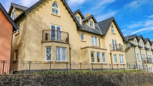 A row of yellow houses with black railings and stone walls. - 3 Rhodewood House (Saundersfoot)