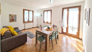 Una sala de estar con sofá, mesa de comedor, sillas y un cuadro en la pared.
