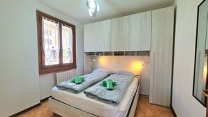 A bedroom with a bed, a window with curtains, a ceiling light, and a wooden cabinet. - Villa La Pief - Gardasee Blick (Tremosine)