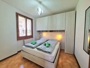 A bedroom with a bed, a window with curtains, a ceiling light, and a wooden cabinet. - Villa La Pief - Gardasee Blick (Tremosine)