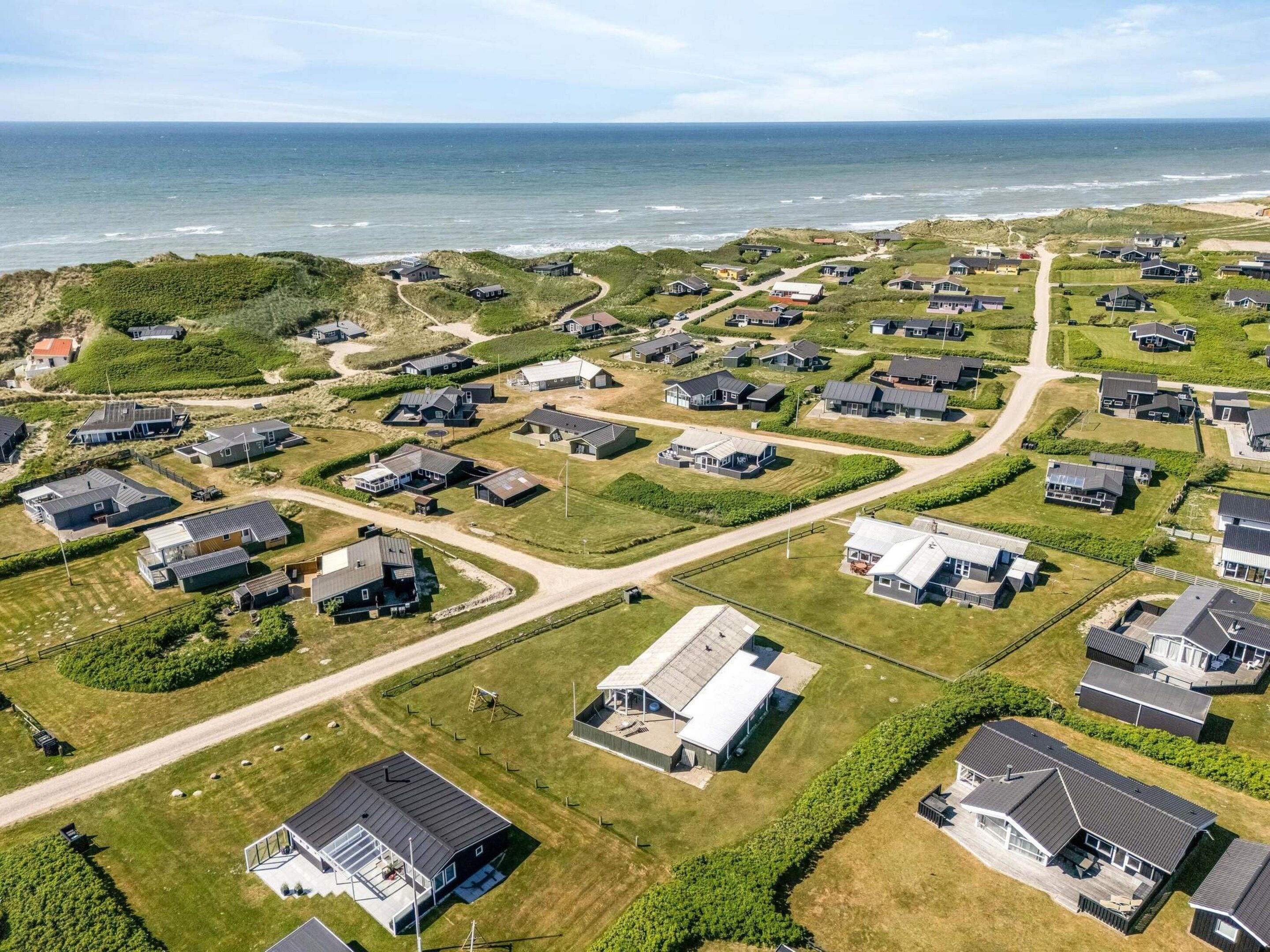 Vista aérea de una zona residencial costera con casas, carreteras y una playa.