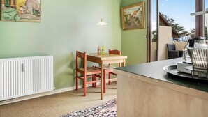 A room with a dining table, chairs, a radiator, a hanging light, and two paintings on the walls. - 4 Star Holiday Home in Lokken (Lokken)