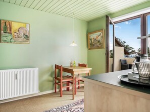 Ein Zimmer mit einem Esstisch, Stühlen, einer Heizung, einem Gemälde und einem Fenster mit Blick.