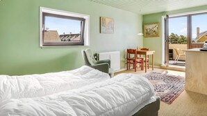 A bedroom with a bed, a desk, a chair, a radiator, a window, and a door leading to an outdoor area. - 4 Star Holiday Home in Lokken (Lokken)