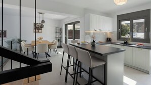 Une cuisine moderne dotée d’un îlot central, de meubles blancs et d’un coin repas avec une table et des chaises.