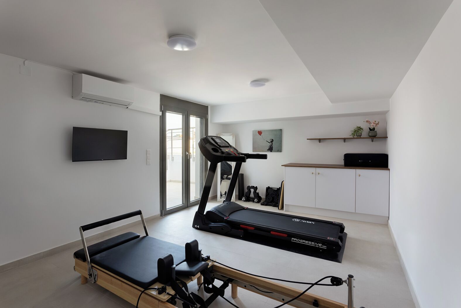 A modern home gym with a treadmill, exercise bike, and a massage table.
