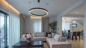 Ein modernes Wohnzimmer mit einer Eckcouch, einem Couchtisch und einem Essbereich mit Stühlen und einem Tisch.