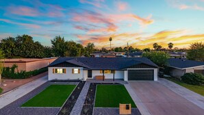 A modern two-story house with a garage, a driveway, and a well-maintained lawn. - Sleeps 16 | Heated Pool + Arcade + Backyard Resort (Mesa)