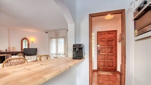 Een moderne keuken met een houten tafel, een koffieapparaat en een televisie.