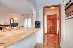 Eine moderne Küche mit einem Holztisch, einer Kaffeemaschine und einem Fernseher.
