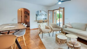 Een moderne woonkamer met een bank, stoelen, een eettafel en een keuken op de achtergrond.