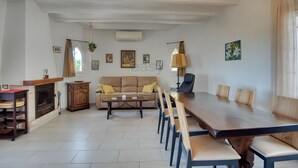 Amplia sala de estar con una gran mesa de comedor de madera, un sofá beige y una chimenea.