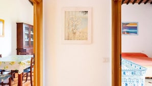 A room with a dining table, a cabinet, a framed picture, and a bed with a patterned bedspread. - Maison Antoinette (San Vincenzo)