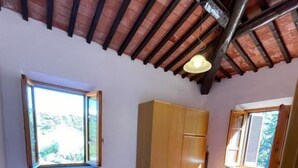 A bedroom with two beds, a wooden wardrobe, a bench, and a window with a view. - Maison Antoinette (San Vincenzo)