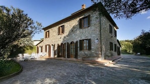 A stone building with a courtyard, arched windows, and outdoor seating. - Maison Antoinette (San Vincenzo)