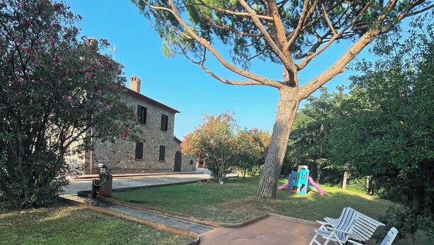 A patio with outdoor furniture, a stone building, and a large tree. - Maison Antoinette (San Vincenzo)