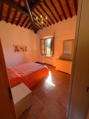 Ein Schlafzimmer mit Bett, Kommode, Fenster und einer Kronleuchter.