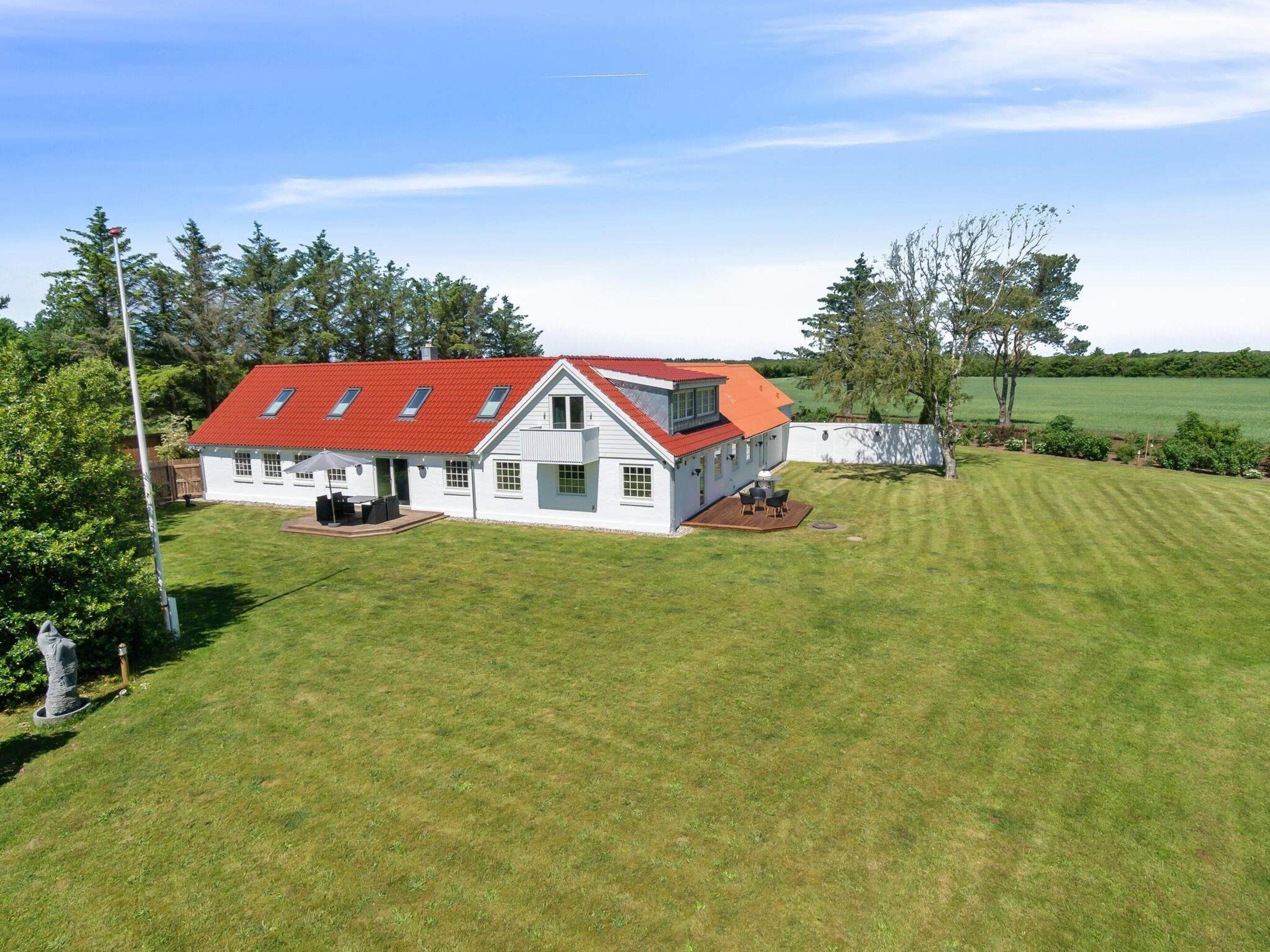 A two-story house with a red roof, a fenced yard, and a well-maintained lawn.