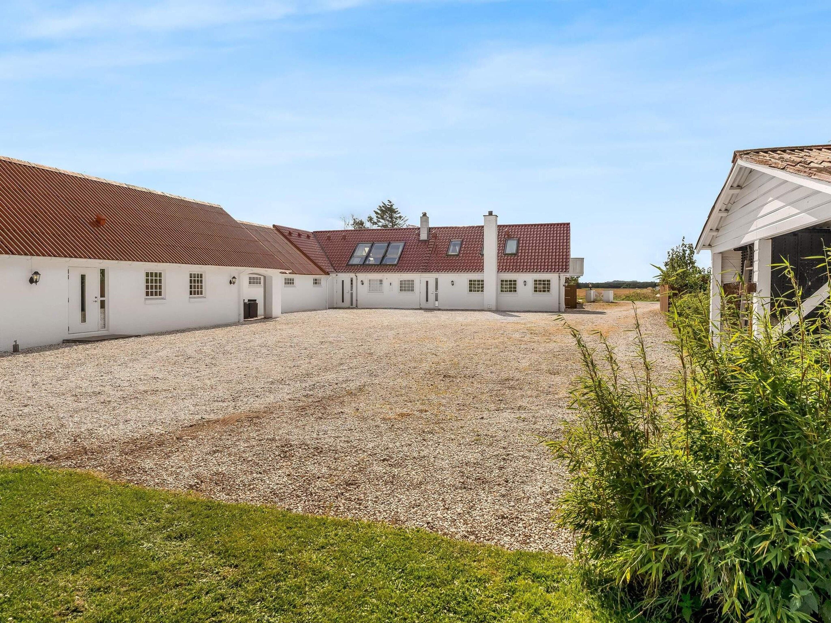 A building with a gravel courtyard, white walls, and red-tiled roofs.