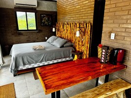 Un dormitorio con una cama, cabecera de madera, una mesa y un banco.