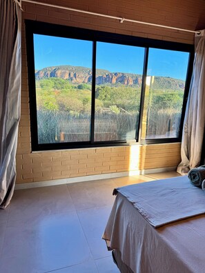 A bedroom with a large window, a bed, and a view of a mountainous landscape. - Sertão do luar (Coronel José Dias)