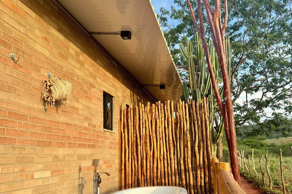 Ein modernes Badezimmer mit einem großen, ovalen Waschbecken, einer Ziegelwand und einem Holzboden.