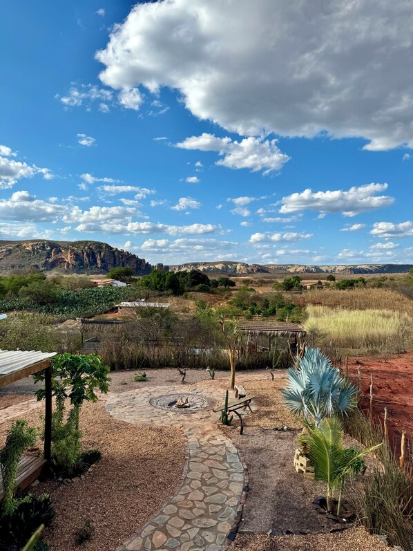 A patio with a stone pathway, a small fire pit, and a cactus plant. - Sertão do luar (Coronel José Dias)