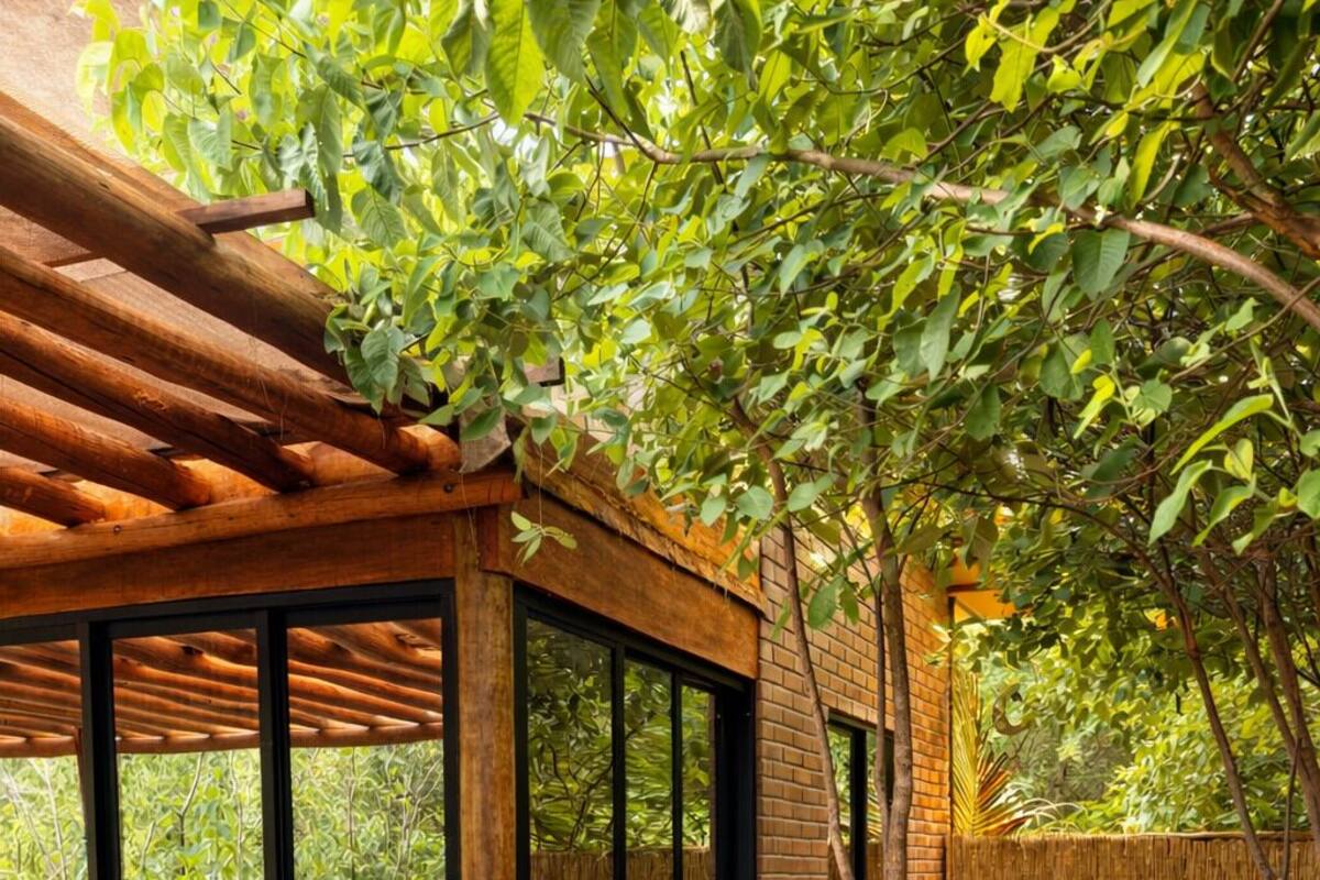 Ein überdachter Außenbereich mit einer Holzpergola, einer Sitzgruppe mit Glasverkleidung und einer großen weißen Whirlpool-Badewanne.