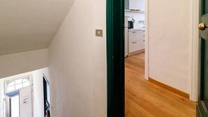 A room with a sloped ceiling, a wooden floor, and a view of a kitchen area. - Apartment in the historic center, Close to Piazza del Campo and the Duomo (Siena)