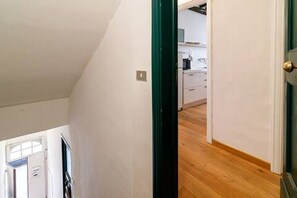 A room with a sloped ceiling, a wooden floor, and a view of a kitchen area. - Apartment in the historic center, Close to Piazza del Campo and the Duomo (Siena)