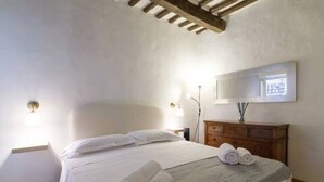 A bedroom with a bed, a wooden dresser, a mirror, and two wall-mounted lights. - Apartment in the historic center, Close to Piazza del Campo and the Duomo (Siena)