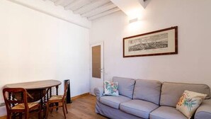 A room with a wooden dining table, two chairs, a grey sofa, and a framed picture on the wall. - Apartment in the historic center, Close to Piazza del Campo and the Duomo (Siena)