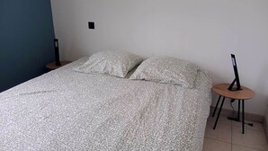 Ein Schlafzimmer mit einem Bett, einem Nachttisch und einem Schreibtisch mit einem Computer.