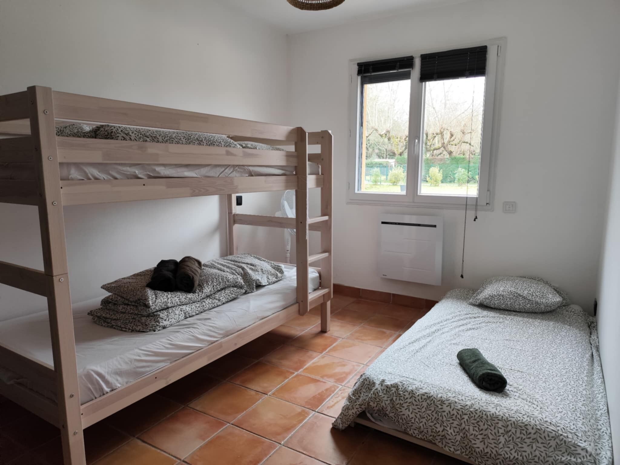 A bunk bed room with a window, radiator, and tiled floor.