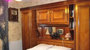 A bedroom with a bed, wooden wardrobe, and a small television. - Bed and Breakfast 'Eugénie' with Mountain View, Shared Terrace and Wi-Fi (La Bourboule)