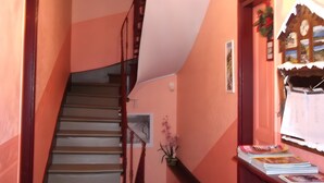 A staircase with wooden handrails, a wall-mounted light fixture, and a door with a decorative window. - Bed and Breakfast 'Eugénie' with Mountain View, Shared Terrace and Wi-Fi (La Bourboule)