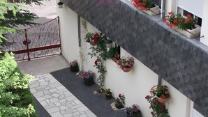 A building exterior with a stone pathway, potted plants, and a metal fence. - Bed and Breakfast 'Eugénie' with Mountain View, Shared Terrace and Wi-Fi (La Bourboule)