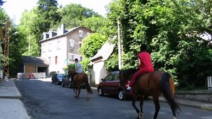 Two individuals riding horses on a street with parked cars and a building in the background. - Bed and Breakfast 'Eugénie' with Mountain View, Shared Terrace and Wi-Fi (La Bourboule)