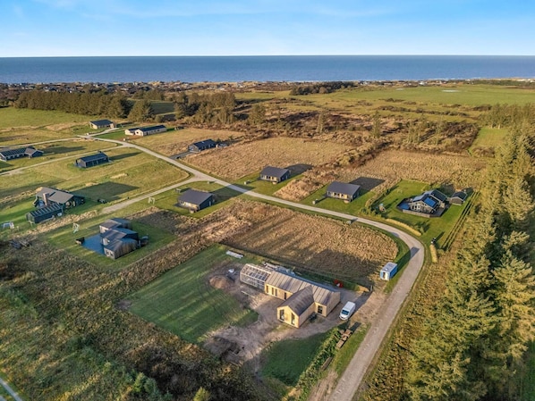 Vista aérea de una zona residencial con casas, un edificio grande y una carretera que conduce al mar.