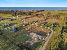 Vista aérea de una zona residencial con casas, un edificio grande y una carretera que conduce al mar.