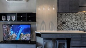 Eine moderne Küche mit einer großen Kochinsel, Barhocker, einem Fernseher und einer Fliesenküchenwand.