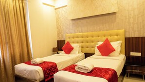 A hotel room with two beds, a wooden headboard, a red and white color scheme, and a patterned wall. - Hotel Golden Amulya Rest Wings (Bengaluru)