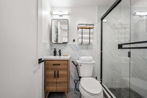 Un baño moderno con inodoro, lavamanos y espejo.