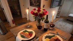 Una mesa de comedor con dos platos de comida, velas y una botella de vino.