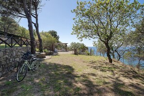 A stone wall, a bicycle, a wooden pergola, and a view of a body of water.