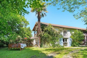 Uma casa com varanda, rodeada por vegetação exuberante e um jardim.