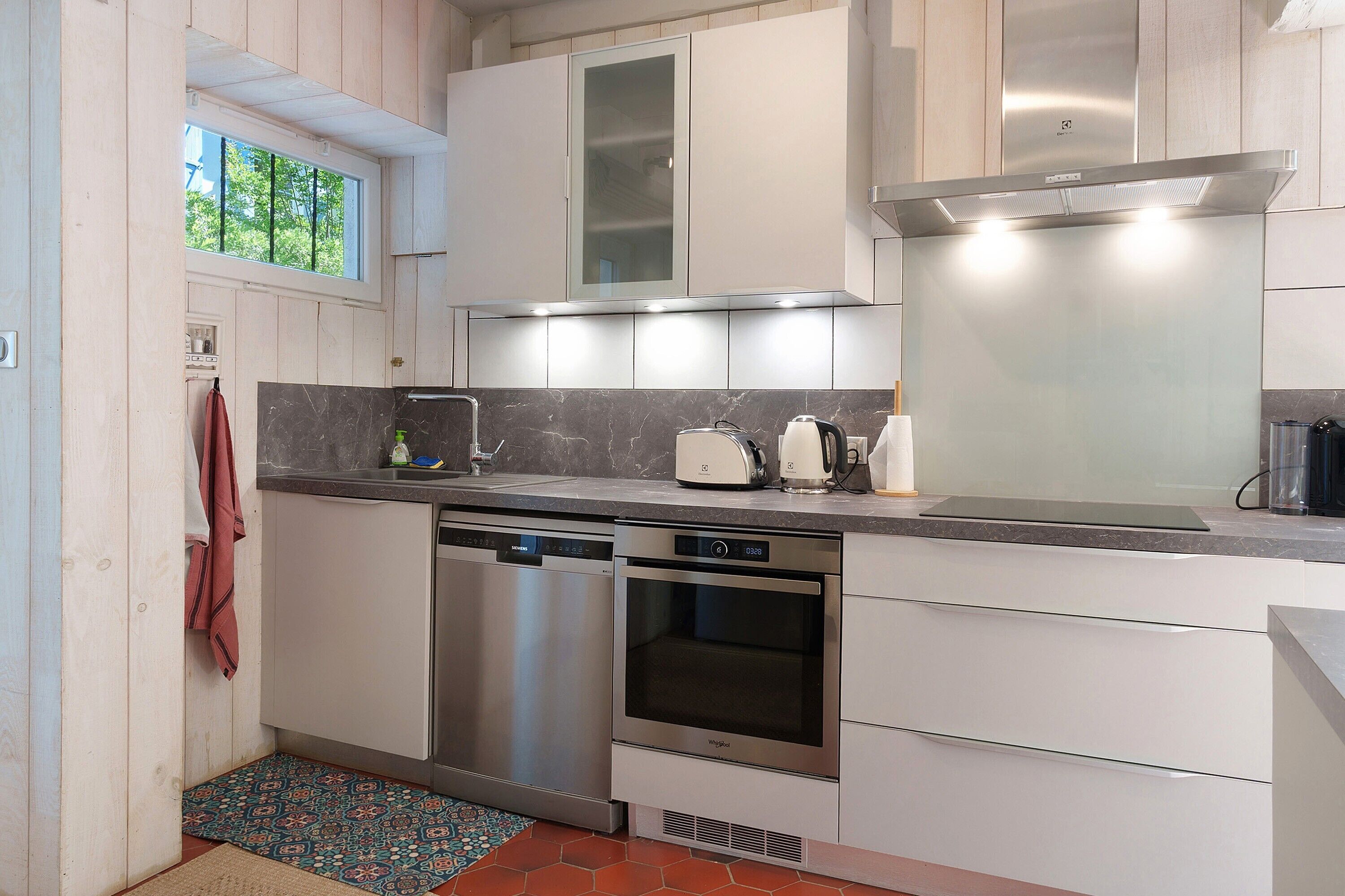 Een moderne keuken met inbouwapparatuur, een raam en een kamerbreed tapijt met een patroon.