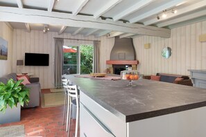 Uma cozinha moderna com uma ilha grande, uma TV de tela plana e um forno embutido.