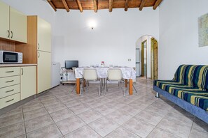 Ein Essbereich mit Tisch, Stühlen, einer Mikrowelle und einem Sofa.
