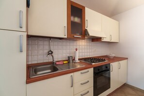 Une cuisine équipée d’un évier, d’une cuisinière, d’un four et de placards.